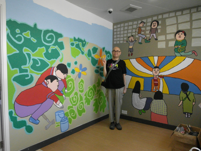 Mak taking picture with both wall paintings