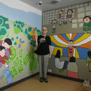 艺术家麦惠鸿和他画的壁画合照